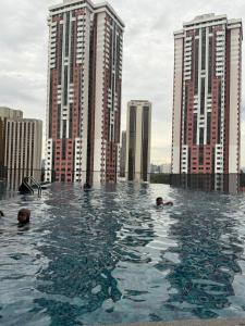a group of people swimming in a pool with tall buildings at City Apartment Chambers Residences KL in Kuala Lumpur