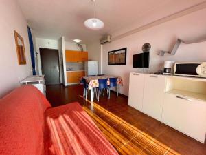 a living room with a kitchen and a table with a television at One-bedroom flat with shared pool in Porto Santa Margherita di Caorle