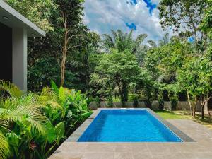 a swimming pool in the middle of a garden at Katsetiu Villas in Kampong Telaga Papan