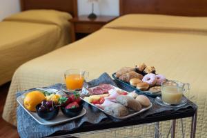 a tray of food with two plates of food on a bed at Residence Acropoli in Syracuse