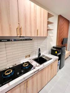una cocina con fregadero y estufa horno superior en Luminera Bali Apartment, en Nusa Dua