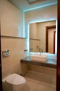 a bathroom with a sink and a toilet and a mirror at Central City View 1BR at Mall Of Islamabad in Islamabad