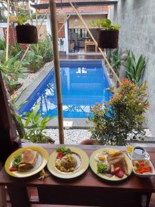 a table with plates of food next to a swimming pool at Nabali House in Kerobokan