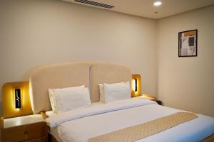 a bedroom with a large bed with white sheets and pillows at Central City View 1BR at Mall Of Islamabad in Islamabad