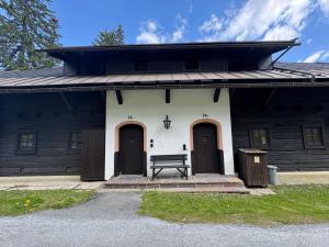 a black and white building with two doors and a bench at Premium Berglodge Nassfeld - direkt an der Piste in Hermagor
