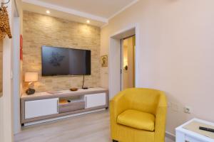 sala de estar con silla amarilla y TV en Apartmani Enna, en Mali Lošinj