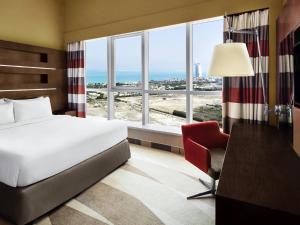 a hotel room with a bed and a desk and window at Novotel Dubai Al Barsha in Dubai