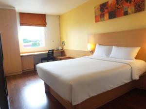 a bedroom with a large white bed and a desk at Ibis Pattaya in Pattaya +63 photos