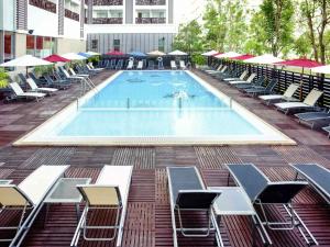 a large swimming pool with lounge chairs and umbrellas at Ibis Pattaya in Pattaya