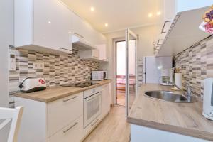 Una cocina con gabinetes blancos y un fregadero. en Apartmani Enna, en Mali Lošinj