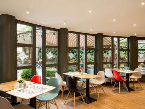 a restaurant with tables and chairs and windows at Ibis Budapest Heroes Square in Budapest