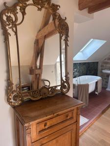 a mirror on top of a wooden dresser with a bath tub at Maisonnette des Sources in Moigny
