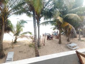 a group of people sitting under palm trees on the beach at Kusuma's Lazy Left hostel in Midigama