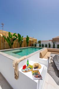 a table with a plate of food next to a swimming pool at Luxury Villa - Sunset Rooftop - Heated Pool - Outdoor Kitchen - Airconditioned in Palm-Mar