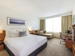 a hotel room with a large bed and a desk at Novotel Christchurch Cathedral Square in Christchurch