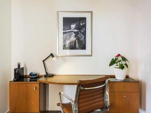 an office with a wooden desk and a chair at Novotel Christchurch Cathedral Square in Christchurch