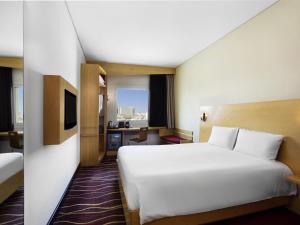 a hotel room with a large white bed and a desk at ibis Muscat in Muscat +42 photos