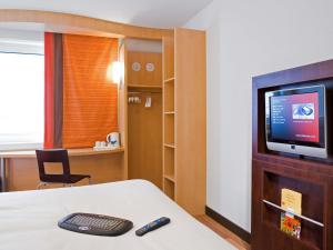 Una habitación con televisión y una cama con control remoto. en ibis Bristol Temple Meads, en Bristol
