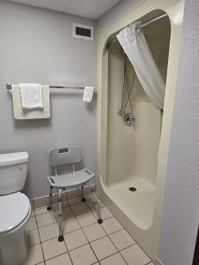 a bathroom with a shower and a toilet and a chair at Sunflower Hotel in Fairfield
