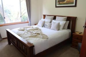 een slaapkamer met een groot bed met witte lakens en kussens bij Black Rock Cottage in Camperdown