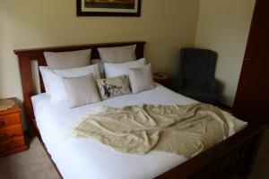 een bed met witte lakens en kussens bij Black Rock Cottage in Camperdown