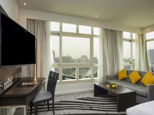 a hotel room with a couch and a desk and a large window at Novotel Cairo El Borg in Cairo