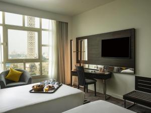 a hotel room with a bed and a desk and a television at Novotel Cairo El Borg in Cairo +46 photos