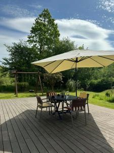 FrederiksværkにあるHoliday Home By Arresø With Bird Sanctuary Next Doorのデッキのパラソル下にテーブルと椅子
