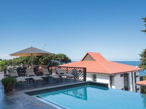 ein Swimmingpool mit Liegestühlen und einem Sonnenschirm neben einem Haus in der Unterkunft ANEW Hotel Ocean Reef Zinkwazi in Zinkwazi Beach