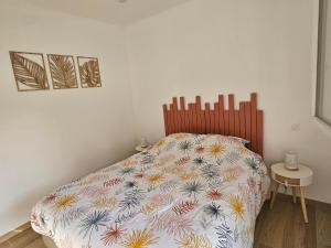 Appartement entouré de verdure في Saint-Martin-de-Seignanx: غرفة نوم مع سرير مع لحاف متهالك