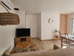 Appartement entouré de verdure في Saint-Martin-de-Seignanx: غرفة معيشة مع طاولة وتلفزيون