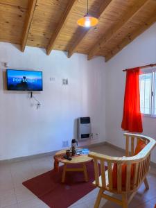 a living room with a table and a tv at Casitas Del Champaqui in Villa Yacanto