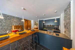 a kitchen with blue cabinets and a stone wall at Le Bouquetin l Ski-out l Sauna in Siviez
