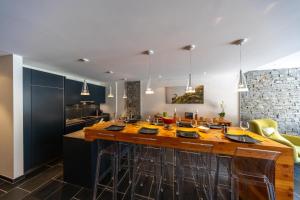 a kitchen with a large wooden island with bar stools at Le Bouquetin l Ski-out l Sauna in Siviez +23 photos