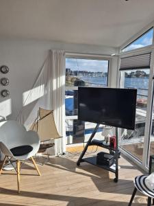 a living room with a flat screen tv and a large window at Schleiverliebt 52 in Schleswig