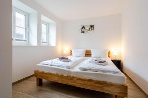 a white bedroom with a large bed with two lamps at Stall in Lehde +16 photos