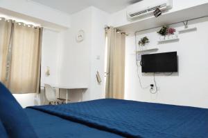 a bedroom with a blue bed and a tv at Antareja LoftVilles By Reccoma in Dukuh