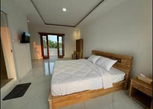 a bedroom with a large bed with white sheets at Greenland Villa in Nusa Lembongan