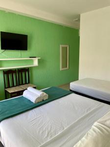 a bedroom with two beds and a green wall at Apart-Hotel "Encantos do Mar" - Beira Mar in Palhoça +105 photos
