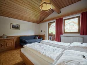 a bedroom with two beds and a couch and a window at Ferienwohnungen Falger in Berwang