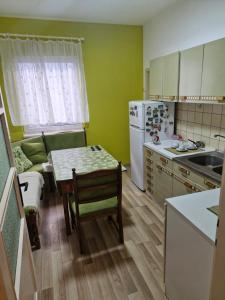a small kitchen with a table and a refrigerator at DiS Apartman in Vršac