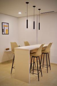 a kitchen with a white counter and chairs at Central City View 1BR at Mall Of Islamabad in Islamabad