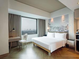 a bedroom with a large white bed and a window at Mercure Jakarta Simatupang in Jakarta