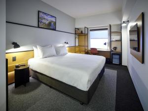 a bedroom with a large white bed and a window at ibis Hamilton Tainui in Hamilton