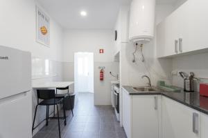 Una cocina blanca con fregadero y encimera. en Casa da Vizinha, en Lisboa