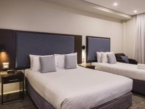 a hotel room with two beds and a chair at Mercure Centro Port Macquarie in Port Macquarie
