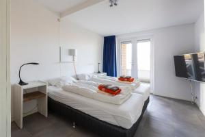 a large white bed in a room with a television at Kabbelaarsbank 506 - Port Marina Zélande NOT INTENDED FOR COMPANY OR WORK-RELATED STAYS in Ouddorp