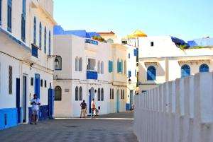 a group of people walking down a street with white buildings at Marina golf location in Asilah