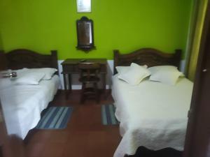 - 2 lits dans une chambre dotée d'un mur vert dans l'établissement POSADA VILLA DEL ROSARiO, à Sutamarchán