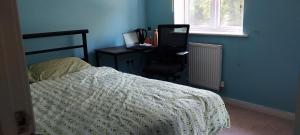 a bedroom with a bed and a desk with a computer at Home stay in Basingstoke